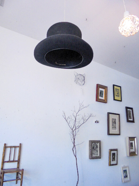 天井から吊るされた帽子、壁にはチェシャ猫の顔も