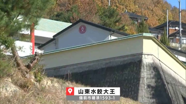 黄色がかった長い塀に囲まれた白い建物が新店舗