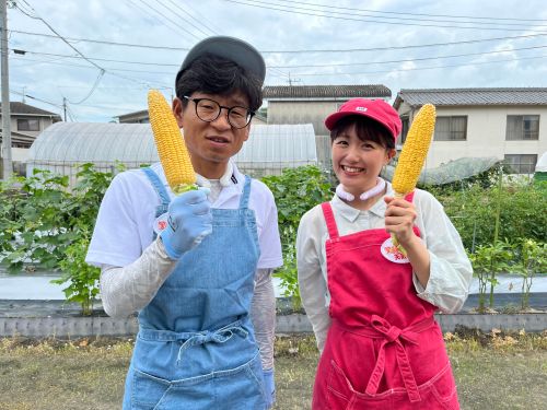 立派に育ったトウモロコシを持つたむたむと難波さん
